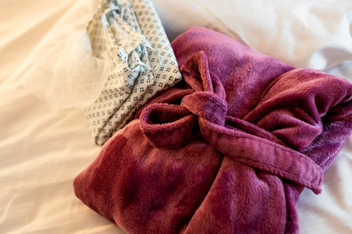 Weicher beerenfarbener Bademantel auf dem Bett